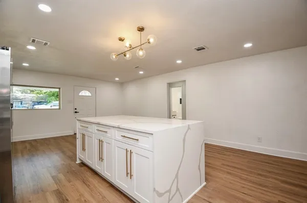 a kitchen that has a microwave a stove and wooden floor