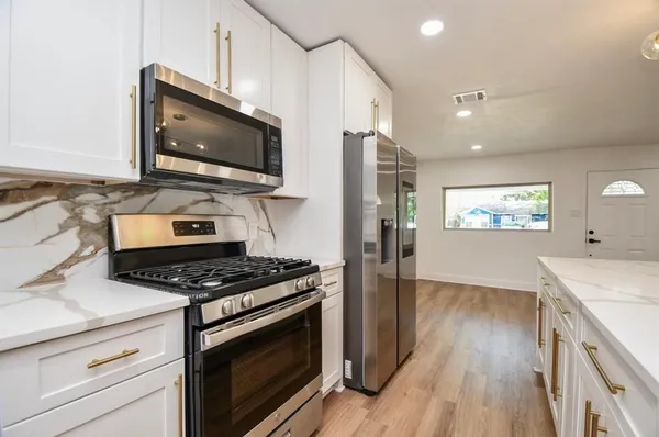 a kitchen with stainless steel appliances granite countertop a stove a microwave and a hard wood floors
