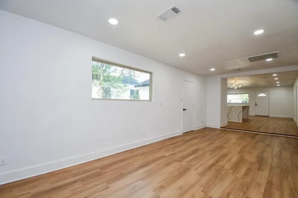 a view of an empty room with wooden floor and a window