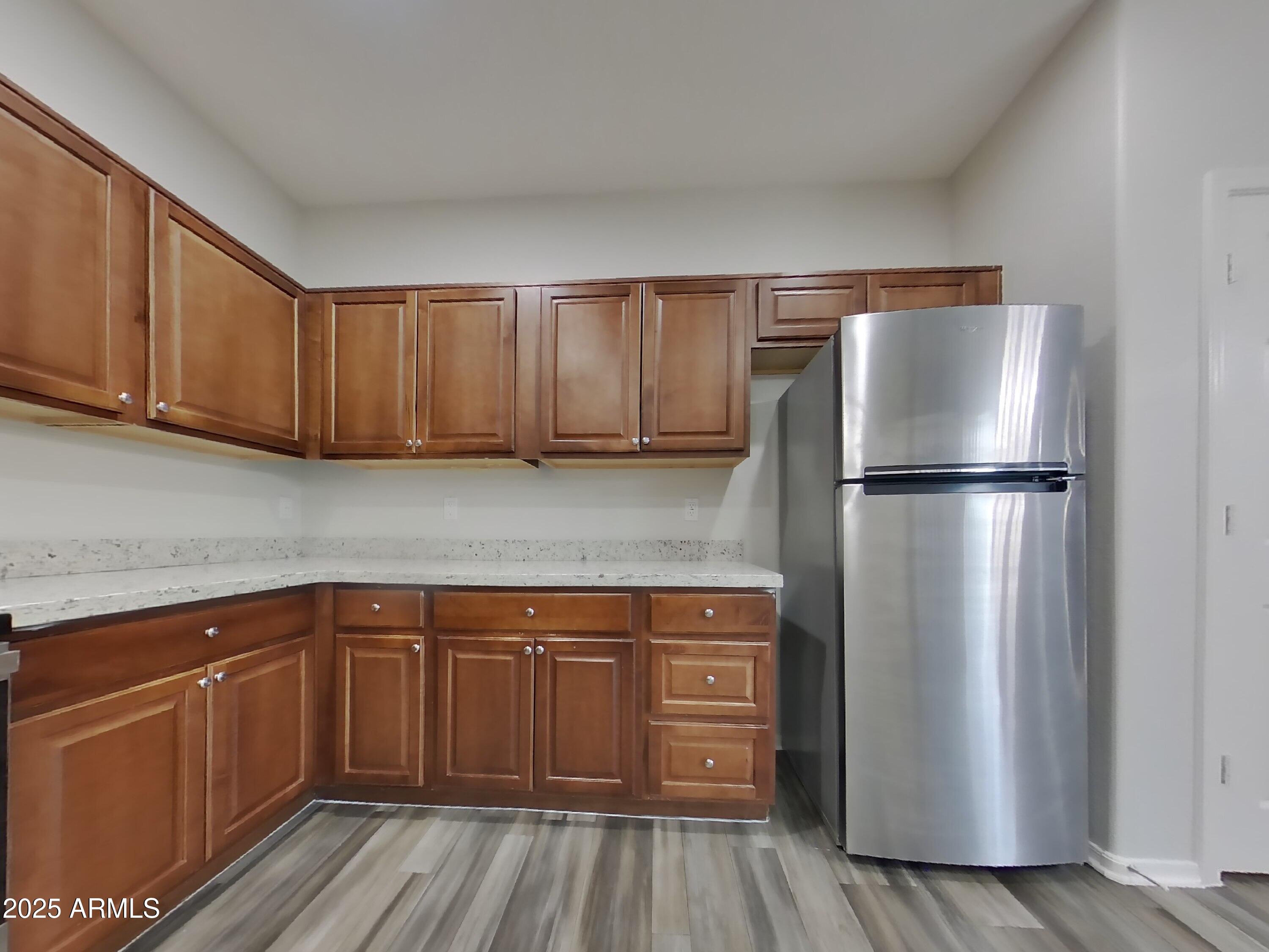 4333 East Ivanhoe Street Gilbert, AZ 85295 - Photo 6 of 16 a kitchen with a refrigerator and wooden cabinets