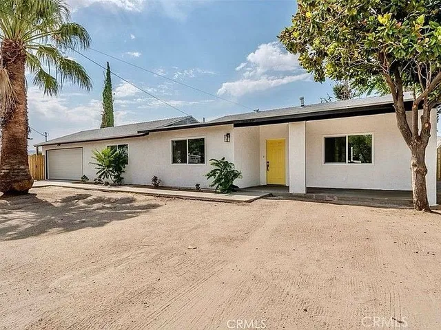a view of a house with a yard and palm trees
