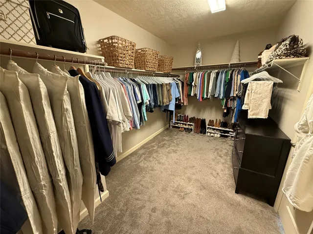 a view of walk in closet with clothes and shoes