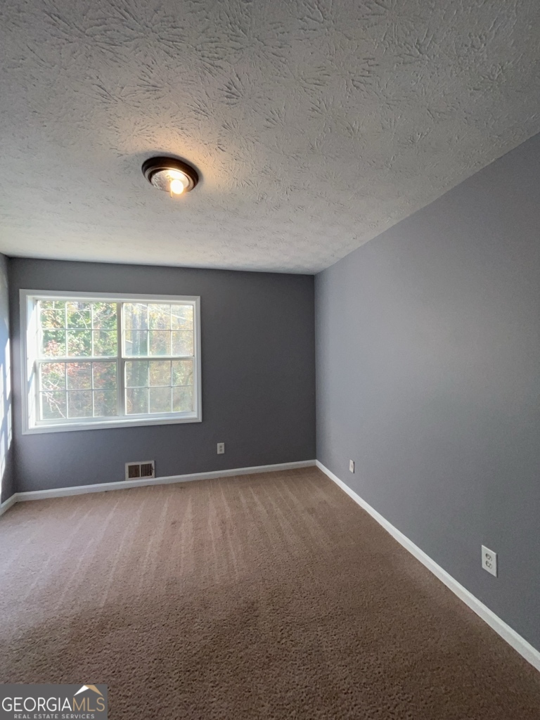 1682 Charmeth Road Lithonia, GA 30058 - Photo 22 of 52 an empty room with wooden floor and windows