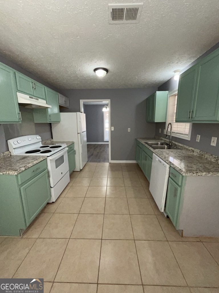 1682 Charmeth Road Lithonia, GA 30058 - Photo 9 of 52 a kitchen with a sink a stove top oven and cabinetry