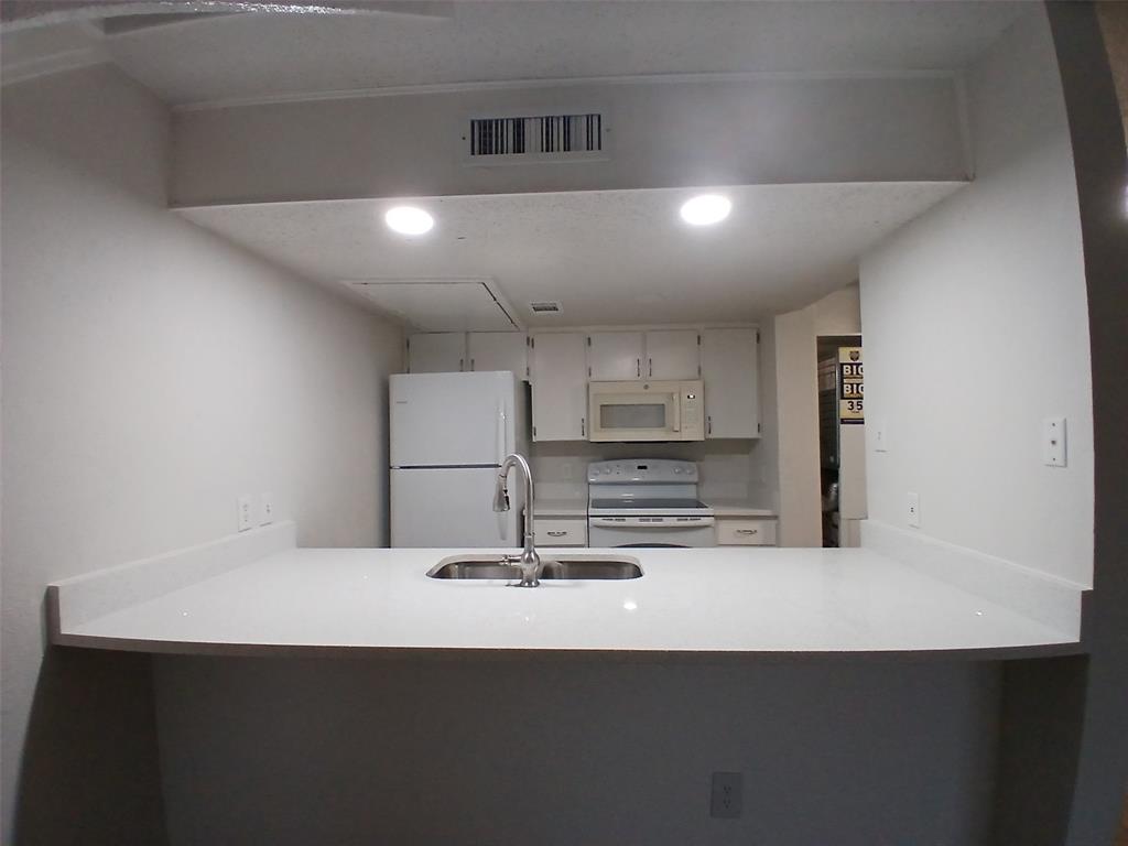 4640 Country Creek Drive, Unit 1257 Dallas, TX 75236 - Photo 4 of 11 a kitchen with kitchen island a sink stainless steel appliances and a refrigerator