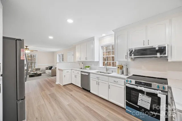 a kitchen with a sink a stove cabinets and wooden floor