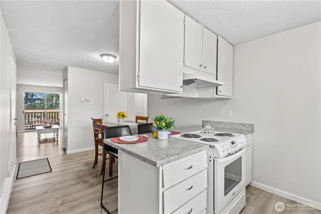 a open kitchen with stainless steel appliances granite countertop a stove and a white cabinets