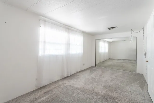 a view of an empty room with window and closet area