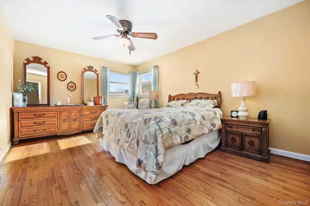 a spacious bedroom with a bed a dresser and wooden floor