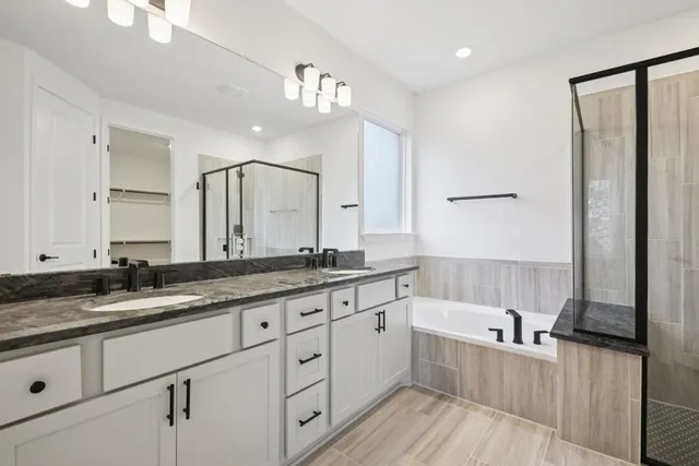 a spacious bathroom with a granite countertop double vanity sink a mirror and a bathtub