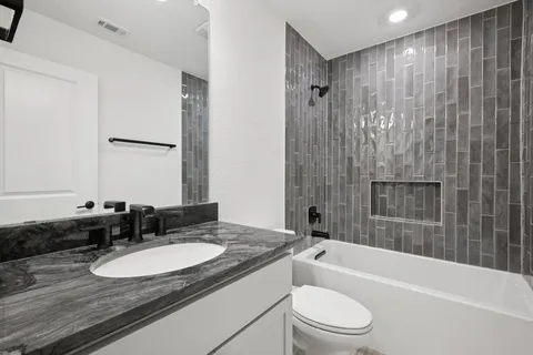 a bathroom with a granite countertop sink toilet and shower