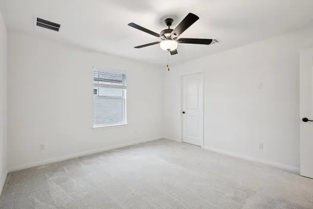 an empty room with windows and fan