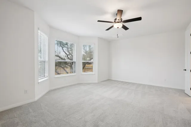 an empty room with a ceiling fan and window