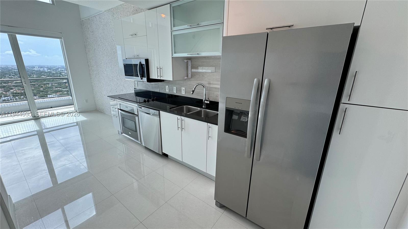 60 Southwest 13th Street, Unit 3015 Miami, FL 33130 - Photo 3 of 14 a kitchen with granite countertop a refrigerator and a sink