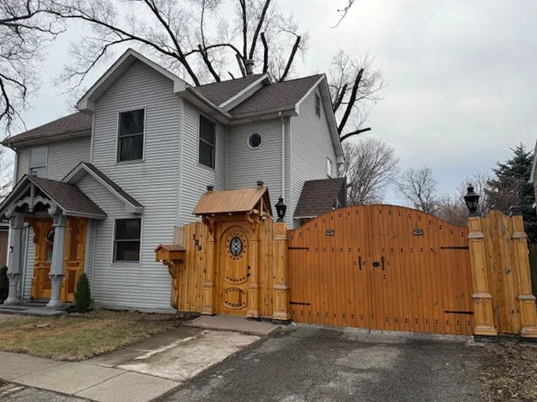 a view of a house with wooden fence next to a yard