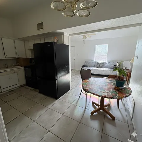 a kitchen with stainless steel appliances kitchen island granite countertop a refrigerator a stove a microwave oven with a dining table and chairs