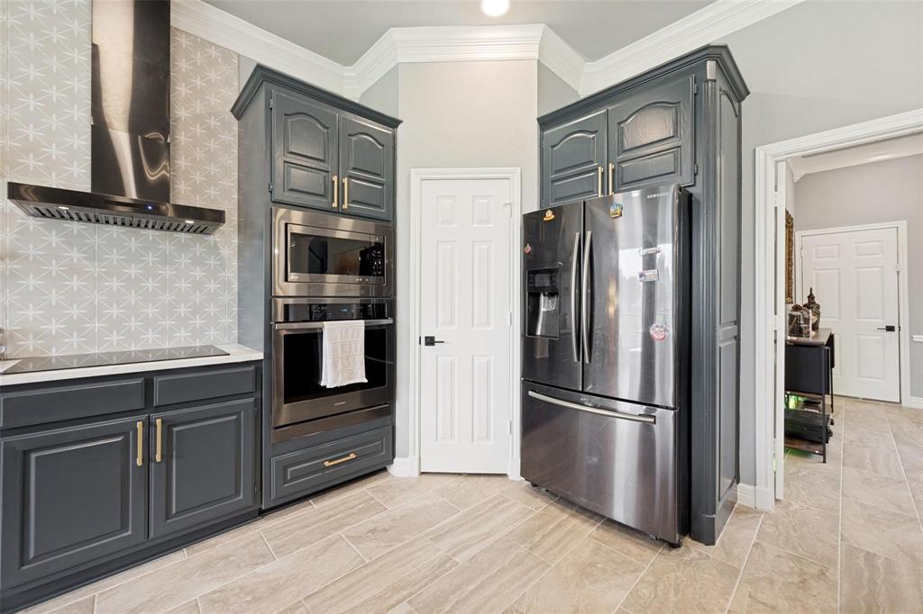 818 Riviera Drive Mansfield, TX 76063 - Photo 18 of 24 Kitchen featuring dark wood cabinetry with gold-tone hardware, a stainless steel range hood, a built-in stainless steel microwave and oven, and light-toned tile flooring