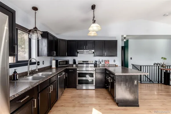 a kitchen with stainless steel appliances granite countertop a sink a stove top oven a counter space and cabinets