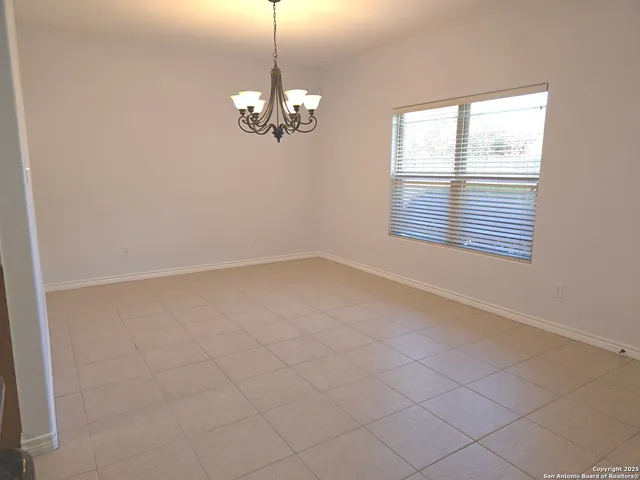 an empty room with chandelier fan and windows