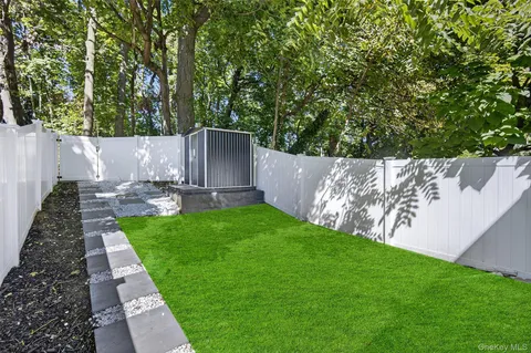 a view of a backyard with plants and large tree
