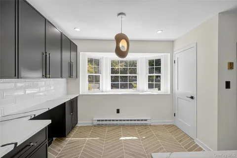 a view of an empty room with a window and kitchen