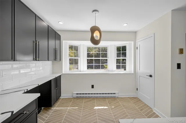 a view of an empty room with a window and kitchen