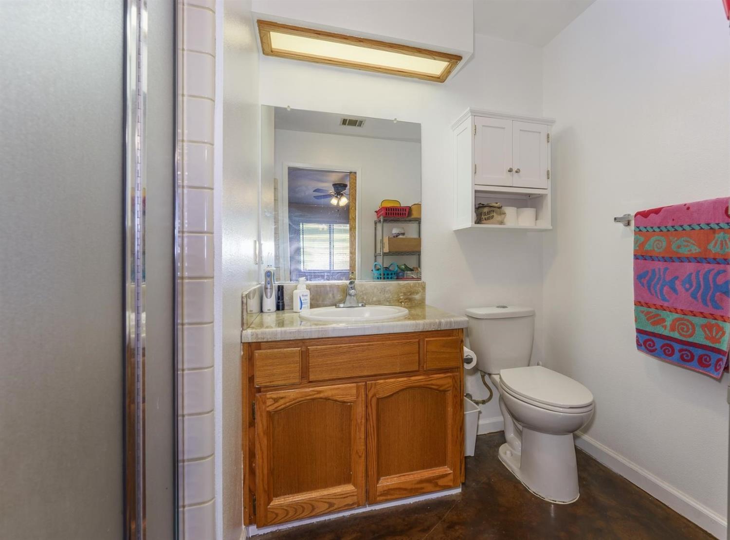 40410 Goldside Drive Oakhurst, CA 93644 - Photo 17 of 24 a bathroom with a granite countertop toilet a sink and a mirror