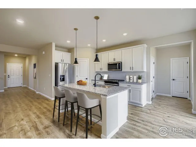 a kitchen with stainless steel appliances kitchen island granite countertop a table chairs and a refrigerator