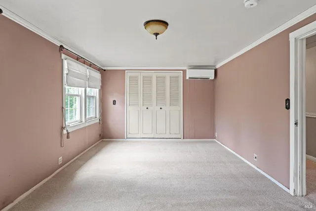 a view of an empty room with window and closet area