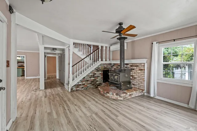 a view of a livingroom with wooden floor a ceiling fan and windows