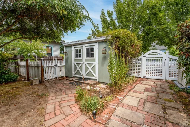 a view of a backyard with large trees and wooden fence