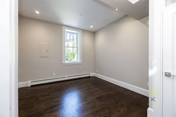 an empty room with wooden floor and window