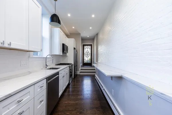 a large kitchen with granite countertop a sink and dishwasher a stove top oven with wooden floor