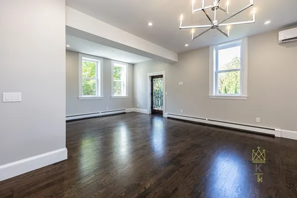 an empty room with wooden floor and windows