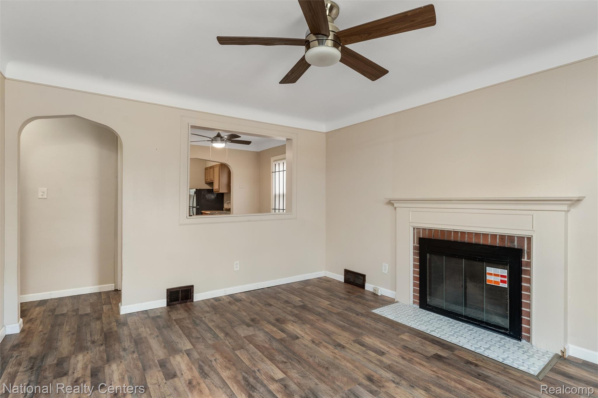5525 Cadieux Road Detroit, MI 48224 - Photo 3 of 19 Unfurnished living room with a fireplace, a ceiling fan, dark wood-type flooring, and arched walkways