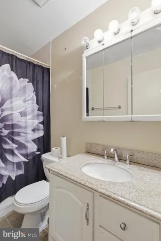 a bathroom with a granite countertop sink a toilet and a mirror