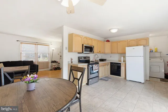 a kitchen with a refrigerator a stove top oven a dining table and chairs