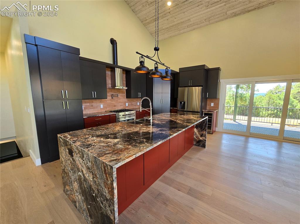33036 Meadow Ridge Lane Trinidad, CO 81082 - Photo 17 of 50 Kitchen featuring hanging light fixtures, appliances with stainless steel finishes, a large island with sink, high vaulted ceiling, and tasteful backsplash