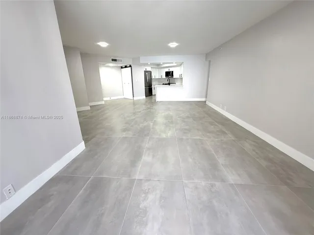 a view of a big room with wooden floor and windows