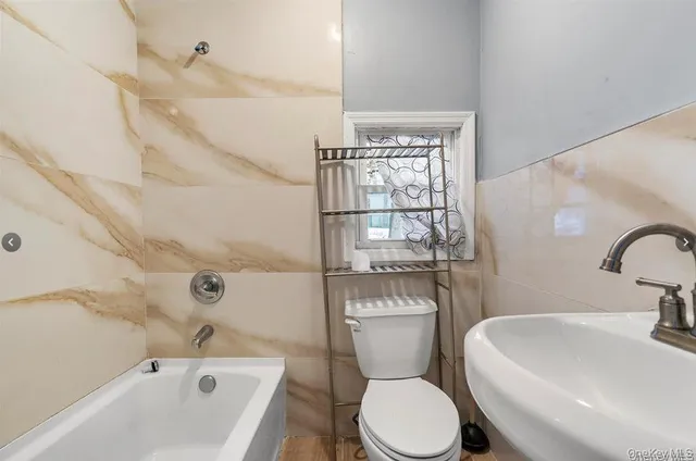 a white toilet sitting next to a bathroom sink and tub