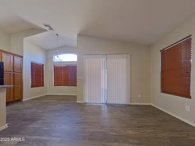 a view of an empty room with glass door and wooden floor