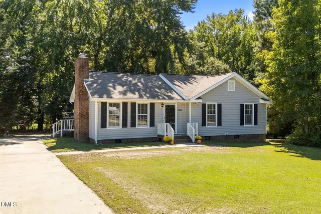 a front view of house with yard and trees in the background