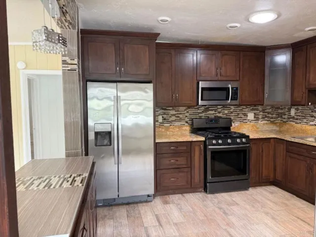 a kitchen with granite countertop stainless steel appliances and wooden cabinets