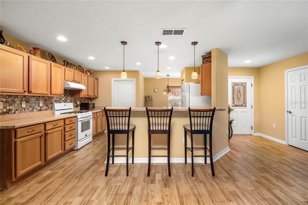 8180 Southwest 80th Terrace Ocala, FL 34476 - Photo 13 of 34 a kitchen with stainless steel appliances a dining table chairs stove refrigerator and cabinets