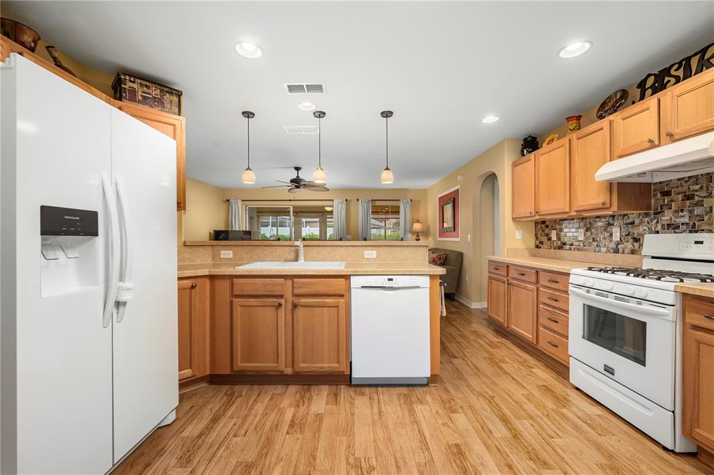 8180 Southwest 80th Terrace Ocala, FL 34476 - Photo 15 of 34 a kitchen with stainless steel appliances granite countertop a refrigerator a stove a sink and white cabinets with wooden floor
