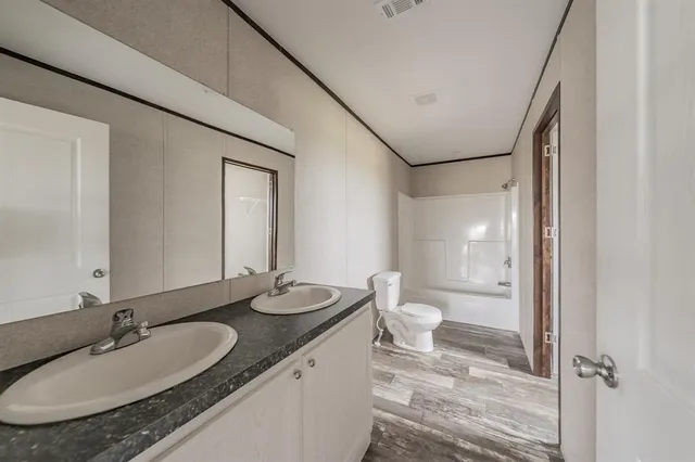 a bathroom with a granite countertop sink mirror and a toilet
