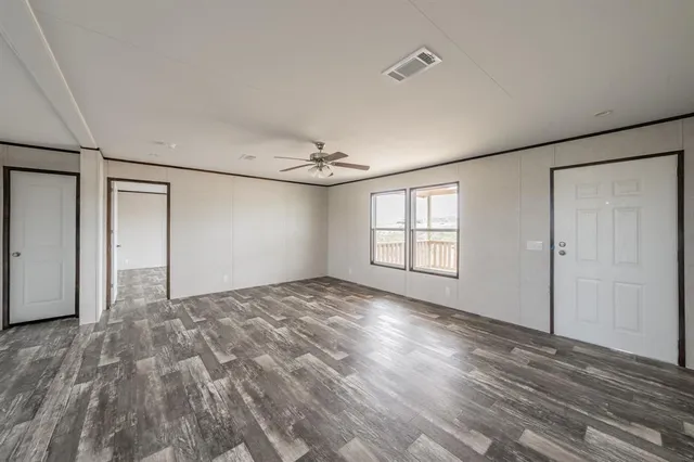 a view of empty room with wooden floor and fan