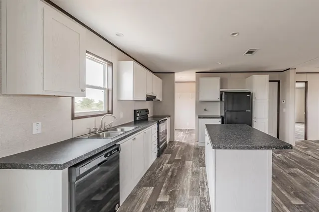 a kitchen with granite countertop a sink a counter space appliances and cabinets