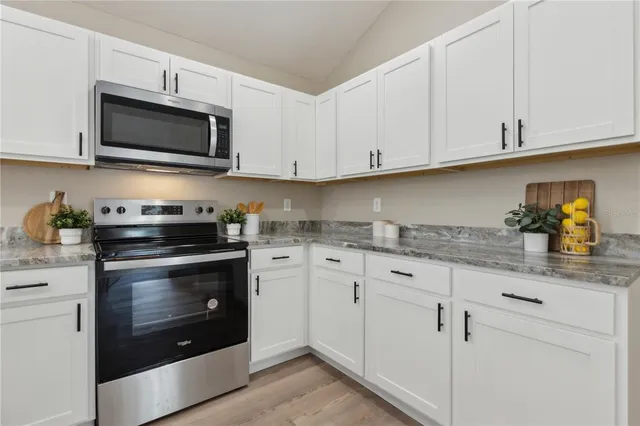 a kitchen with granite countertop white cabinets stainless steel appliances and sink