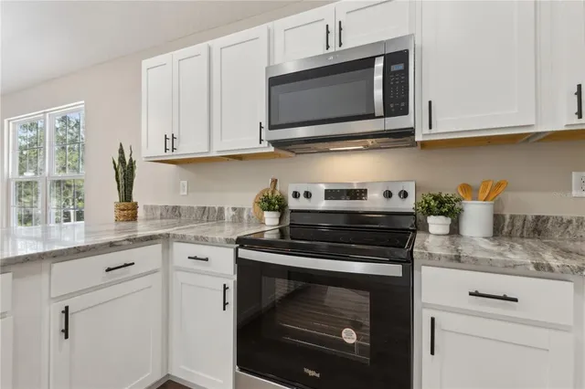 a kitchen with stainless steel appliances granite countertop white cabinets granite counter tops and a wooden floors